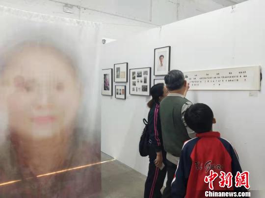 在第19屆中國平遙國際攝影大展柴油機展區(qū)的一角，一張大幅的人像彩畫吸引來往游客駐足拍照。　楊佩佩 攝