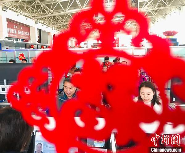 “春節(jié)裝飾”扮靚出入境邊防檢查執(zhí)勤現(xiàn)場。圖為民眾排隊通過驗證臺?！“瑧c龍 攝