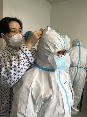 3  王泠（左后）在為護(hù)理隊(duì)員仔細(xì)整理防護(hù)服，叮囑她們?cè)谧龊霉ぷ鞯耐瑫r(shí)一定要注意保護(hù)好自己。
