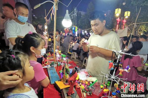 資料圖：圖為手工藝人在夜晚走上街頭，展示面塑工藝。　趙曉 攝
