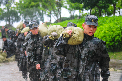 圖為在安徽合肥巢湖任務區(qū)官兵在暴雨中扛運沙袋，加固堤壩。（王文洲 攝）